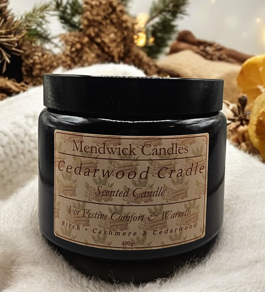 Mendwick Cedarwood Cradle 400g candle shown on  a soft throw with pine needles, cedarwood and lemon zest in the back ground