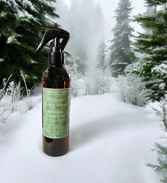 Frosted Evergreens scented room spray shown on snowy floor with snow dusted evergreens in the back ground