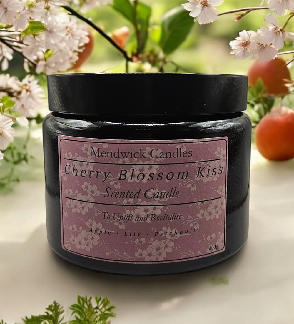 Mendwick Candles Cherry Blossom Kiss 400g Scented Candle shown on a white table, with cherry blossoms and oranges in the background