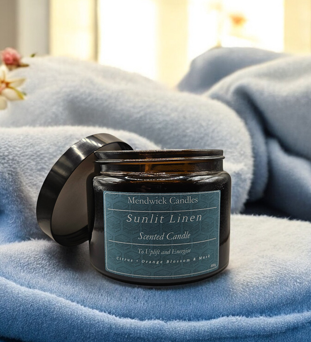 Lifestyle Shot of Sunlit Linen Scented Candles, lay on a soft blue towel