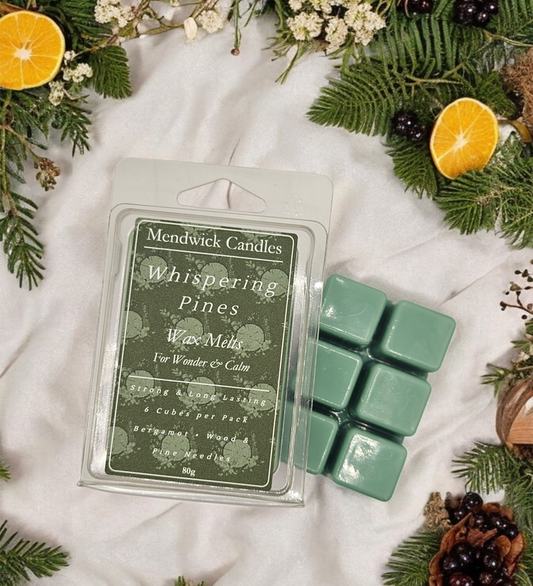 Whispering Pines Wax Melts shown surrounded by pine, bergamot and orange